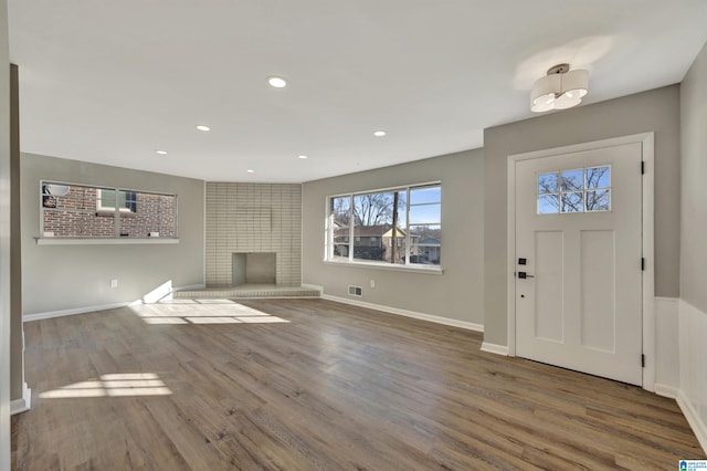 entryway featuring hardwood / wood-style flooring and a brick fireplace