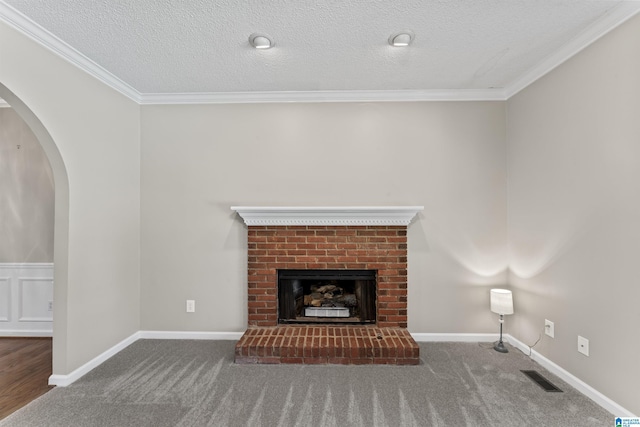 unfurnished living room featuring dark carpet, a textured ceiling, a brick fireplace, and ornamental molding