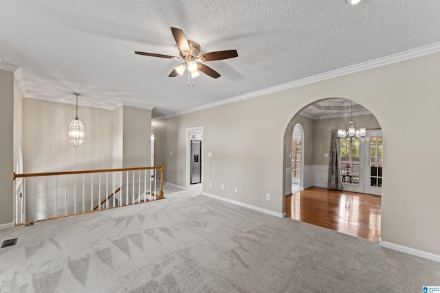 carpeted spare room featuring a notable chandelier, ornamental molding, and a textured ceiling