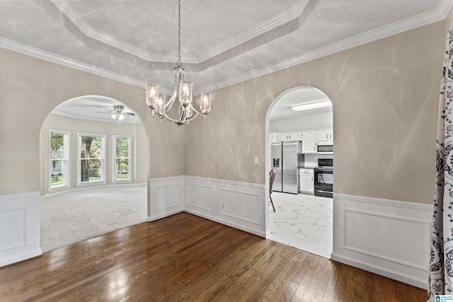 unfurnished dining area with ceiling fan, a raised ceiling, ornamental molding, and dark hardwood / wood-style floors