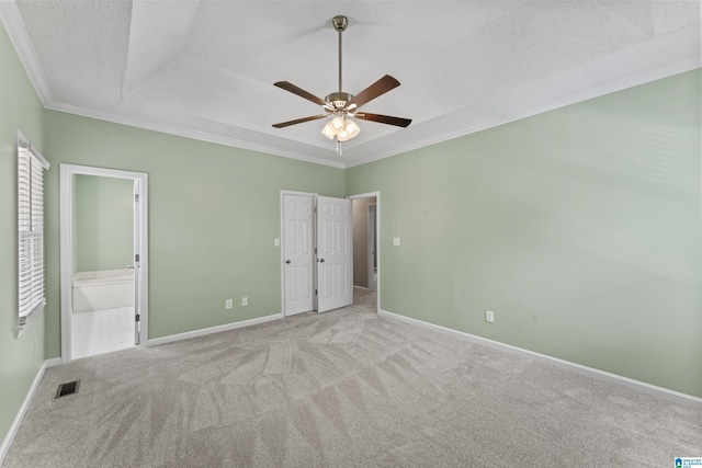 unfurnished bedroom with a textured ceiling, light carpet, ornamental molding, ceiling fan, and ensuite bathroom