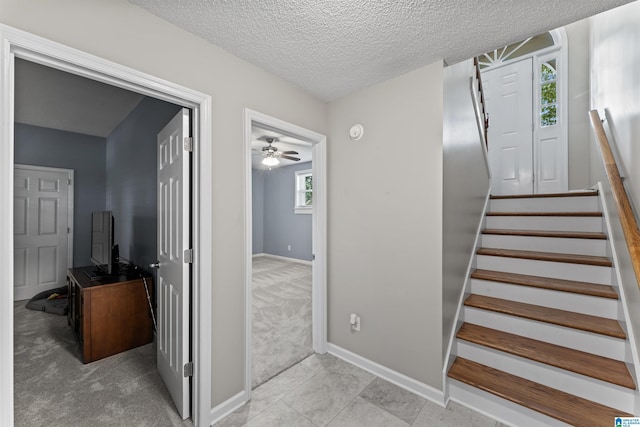 stairway with a textured ceiling and carpet floors