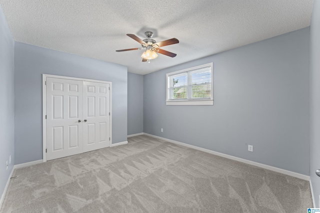 unfurnished bedroom featuring a closet, ceiling fan, light colored carpet, and a textured ceiling