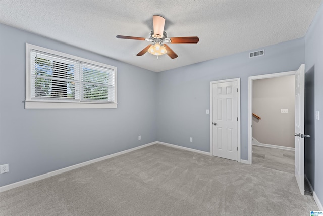 carpeted empty room with ceiling fan and a textured ceiling