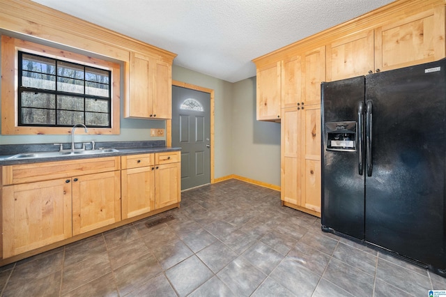 kitchen with sink, light brown cabinets, a textured ceiling, and black fridge with ice dispenser