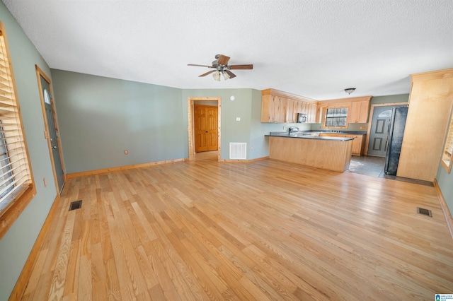 kitchen featuring black appliances, light brown cabinetry, kitchen peninsula, ceiling fan, and light hardwood / wood-style flooring