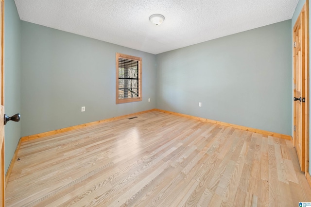 spare room with a textured ceiling and light wood-type flooring