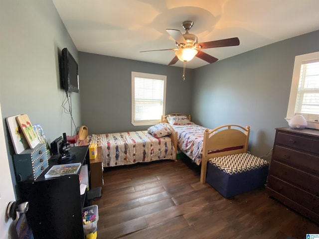 bedroom with ceiling fan, dark wood-type flooring, and multiple windows