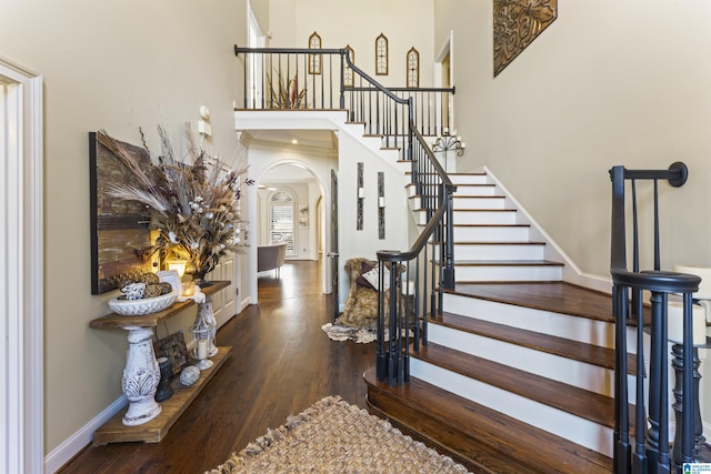 staircase with hardwood / wood-style floors and a towering ceiling