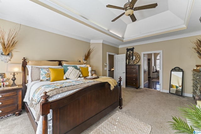 bedroom with ensuite bathroom, light carpet, a raised ceiling, ornamental molding, and ceiling fan