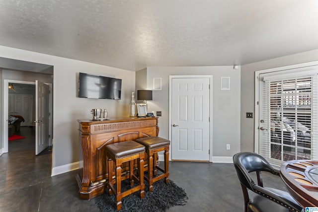 miscellaneous room with indoor bar and a textured ceiling