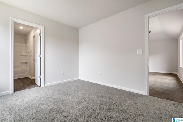 spare room featuring lofted ceiling and dark carpet