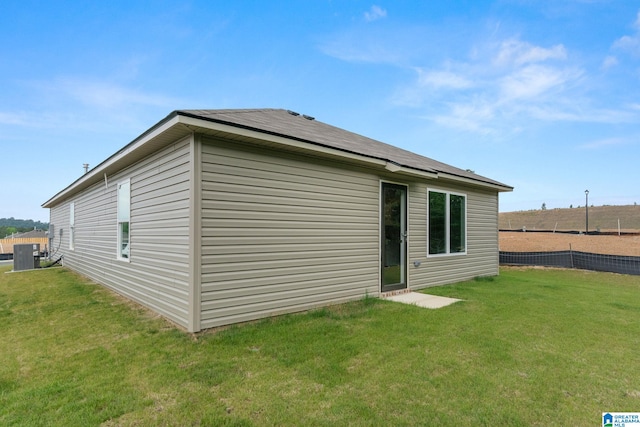 rear view of property with a yard and central air condition unit