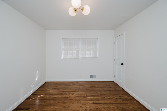 unfurnished room with an inviting chandelier and dark hardwood / wood-style floors