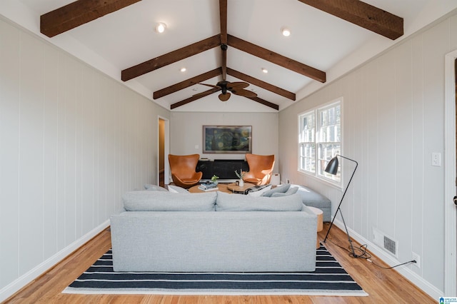 living room featuring vaulted ceiling with beams, ceiling fan, and light wood-type flooring