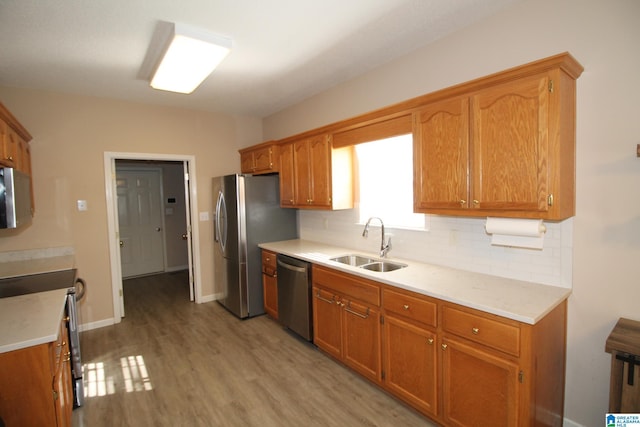 kitchen featuring decorative backsplash, sink, stainless steel appliances, and light hardwood / wood-style floors