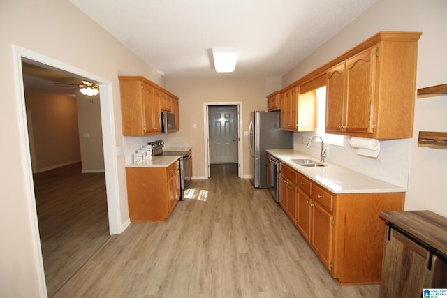 kitchen featuring light hardwood / wood-style floors, appliances with stainless steel finishes, decorative backsplash, sink, and ceiling fan