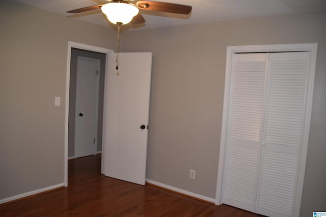 unfurnished bedroom with dark wood-type flooring, a closet, and ceiling fan