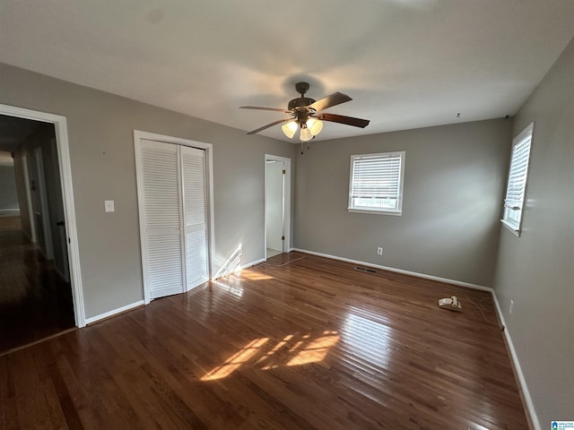 unfurnished bedroom with dark hardwood / wood-style floors, two closets, and ceiling fan