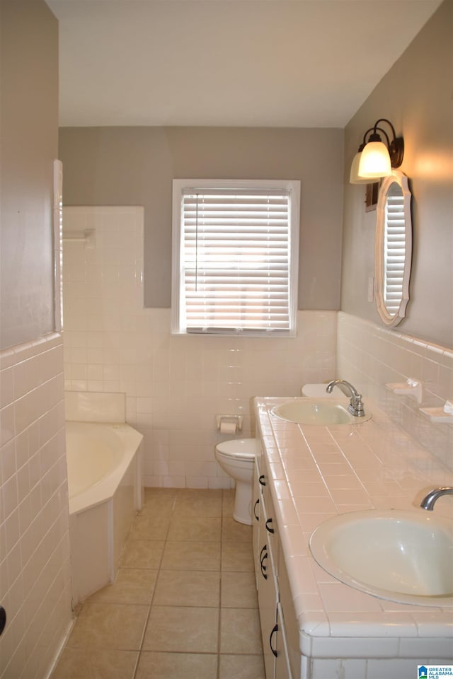 bathroom with tile patterned flooring, tile walls, toilet, vanity, and a washtub