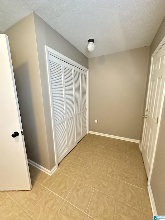 unfurnished bedroom with a closet, light tile patterned floors, and a textured ceiling