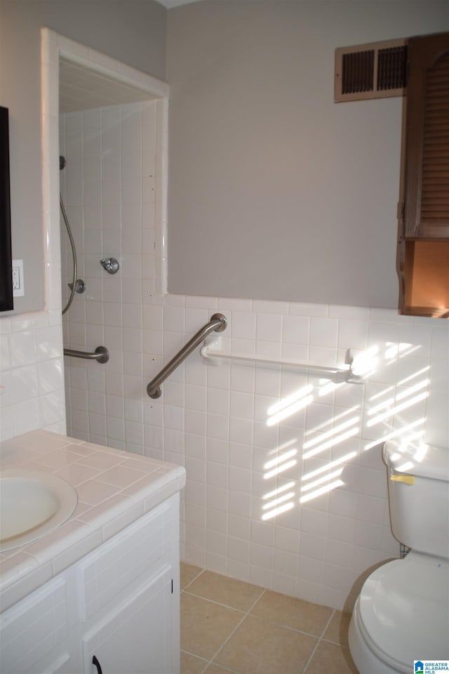 bathroom with tile patterned floors, toilet, tile walls, and vanity