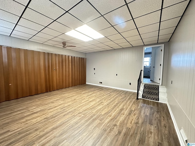 basement featuring a paneled ceiling and light hardwood / wood-style flooring