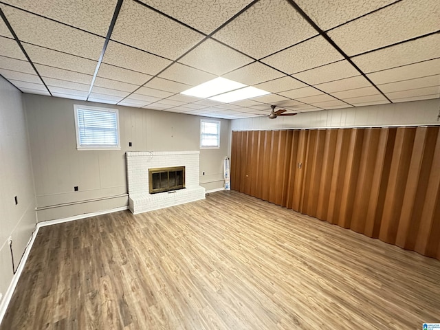 basement featuring a fireplace, hardwood / wood-style floors, and a paneled ceiling