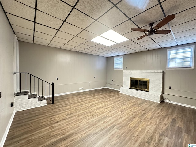 basement with plenty of natural light, a drop ceiling, and a brick fireplace