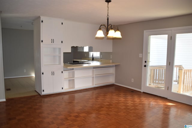 kitchen featuring decorative light fixtures, white cabinets, black electric stovetop, dark parquet flooring, and a notable chandelier