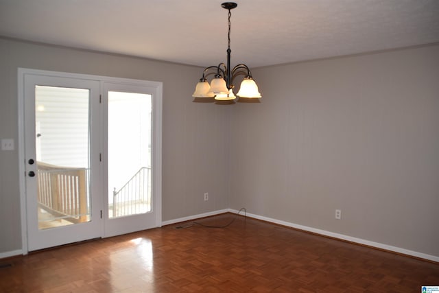 empty room featuring dark parquet flooring and a chandelier