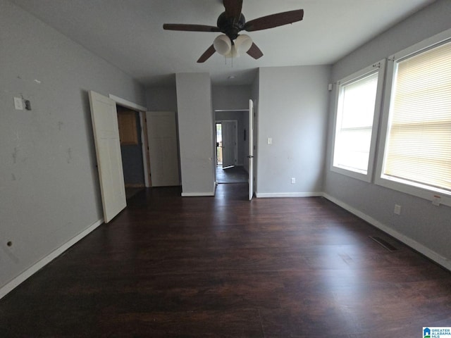 empty room with ceiling fan and dark hardwood / wood-style flooring