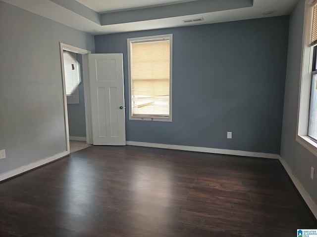 unfurnished room with dark hardwood / wood-style floors and a tray ceiling