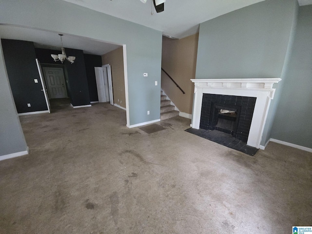 unfurnished living room with carpet floors, ceiling fan with notable chandelier, and a fireplace