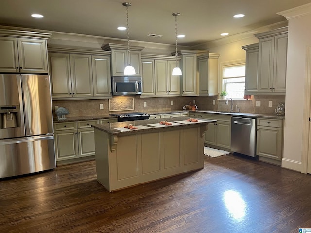 kitchen featuring pendant lighting, crown molding, stainless steel appliances, and a center island