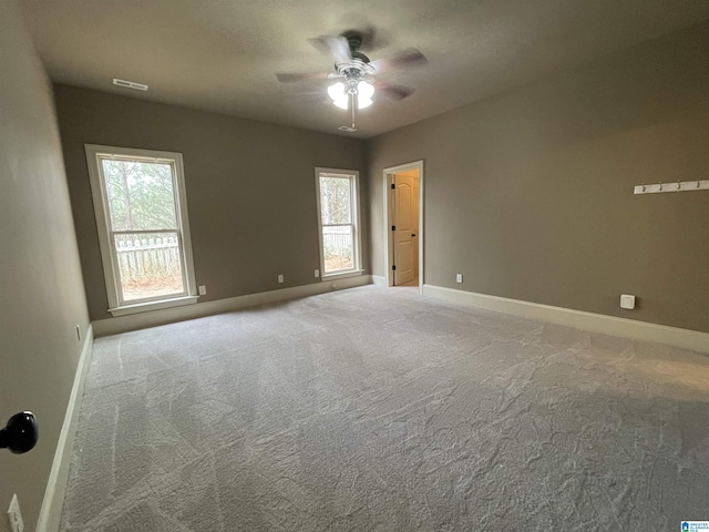 carpeted empty room with ceiling fan and plenty of natural light