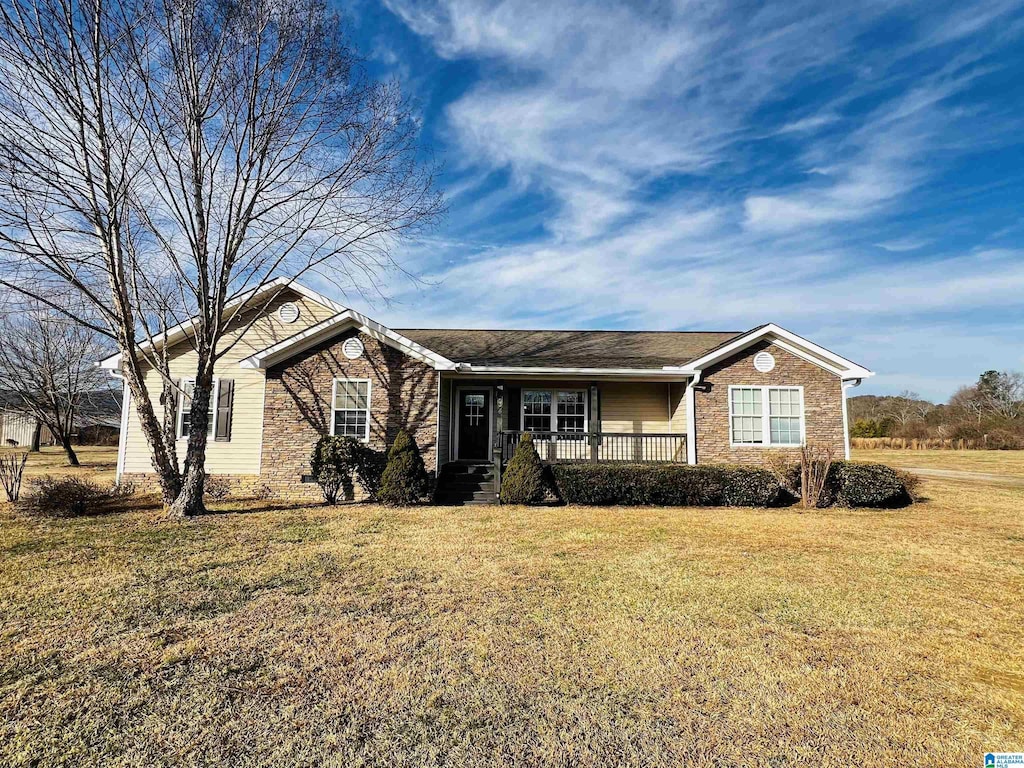 ranch-style home featuring covered porch and a front lawn