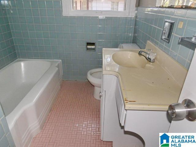 bathroom with tile walls, toilet, and vanity