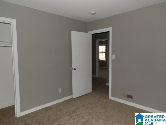 unfurnished bedroom featuring light carpet and a closet