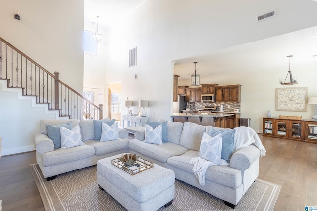 living room featuring a chandelier, light hardwood / wood-style flooring, and a high ceiling