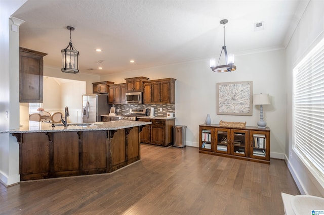 kitchen with sink, hanging light fixtures, appliances with stainless steel finishes, and a kitchen breakfast bar