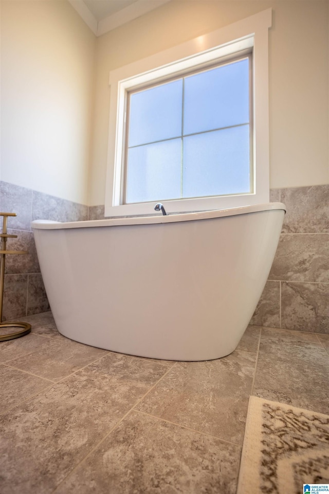 bathroom featuring a healthy amount of sunlight, tile walls, and a tub