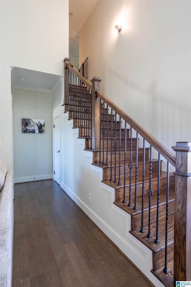 stairway with crown molding and wood-type flooring