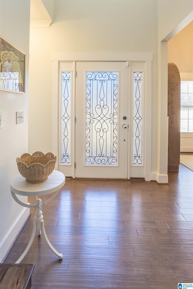 foyer entrance with crown molding and dark wood-type flooring