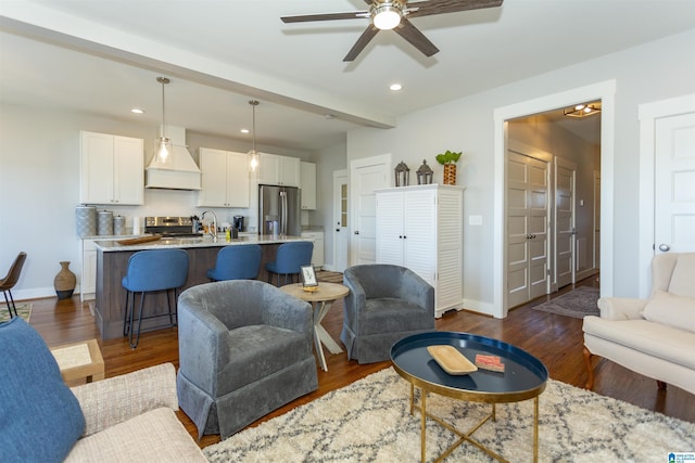 living room with dark hardwood / wood-style flooring, beam ceiling, and ceiling fan