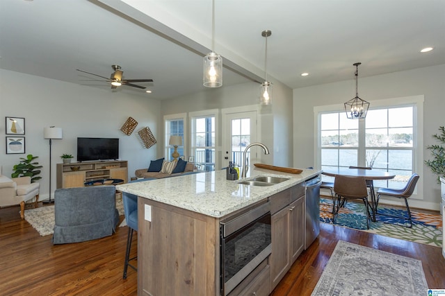 kitchen with stainless steel appliances, sink, a kitchen island with sink, and decorative light fixtures