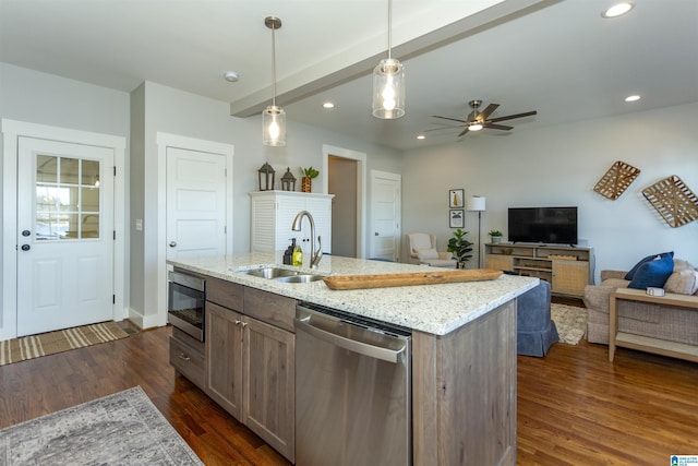 kitchen featuring appliances with stainless steel finishes, decorative light fixtures, sink, a kitchen island with sink, and light stone countertops