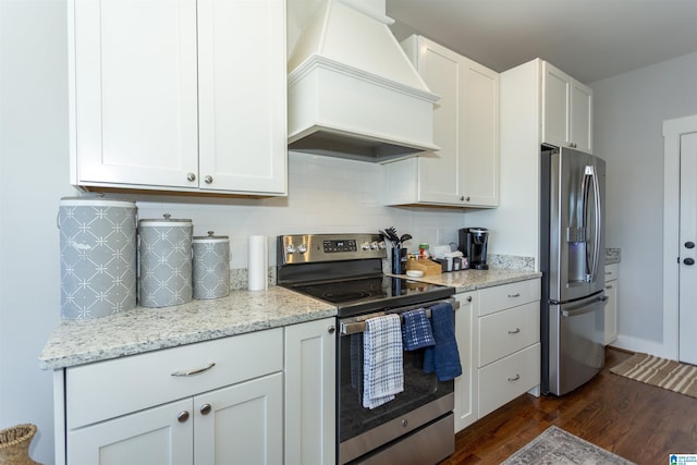 kitchen featuring premium range hood, appliances with stainless steel finishes, white cabinetry, dark hardwood / wood-style flooring, and light stone counters