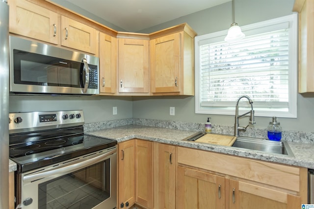 kitchen with sink, light brown cabinetry, hanging light fixtures, and stainless steel appliances