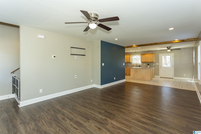 unfurnished living room featuring sink, hardwood / wood-style flooring, and ceiling fan